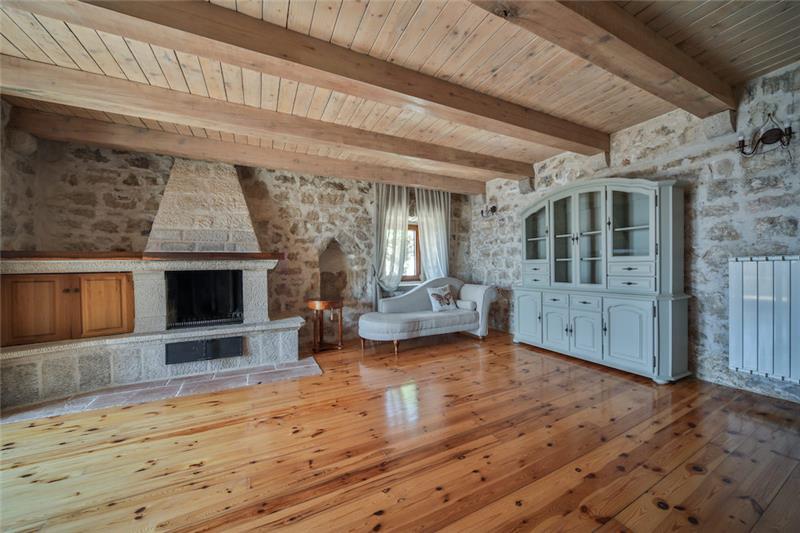 A stone sitting room with a fireplace and beamed ceiling near Petrovac, Montenegro