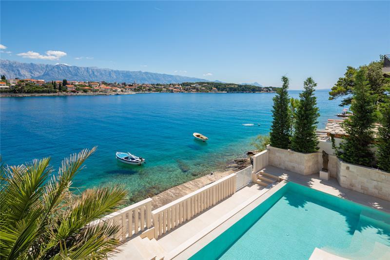 Small boats moored in clear water off a village on Brač, mountains across the channel