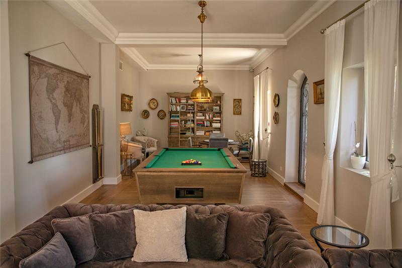 A sitting room with a full bookcase, billiard table and brass lamps in the Budva Region, Montenegro